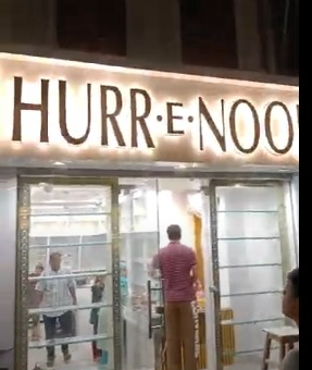 Illuminated storefront sign with bold lettering above a modern glass-front entrance.